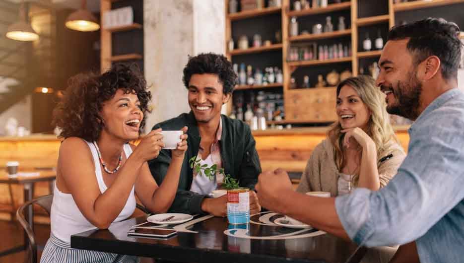 Young friends having a great time in restaurant. Multiracial group of young people sitting in a coffee shop and smiling.